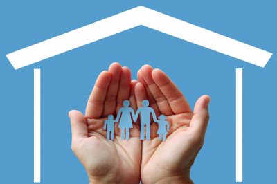 Paper,Family,In,Hands,With,Home,On,Blue,Background,Welfare